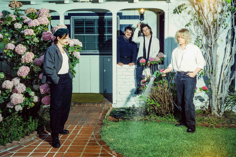 Australian indie rock band Vacations posing outside a house with hydrangeas, photographed by Pooneh Ghana